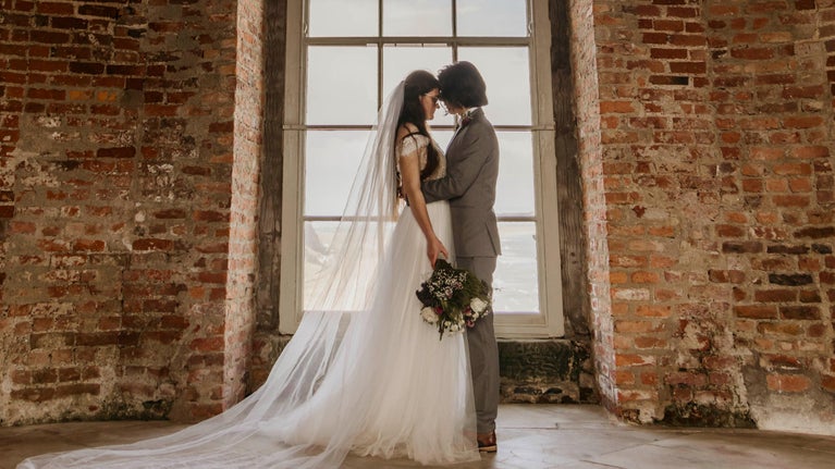 A bride and groom standing in front of the tall windows at Mussenden Temple.
